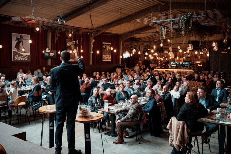 A speaker addressing an audience seated at tables