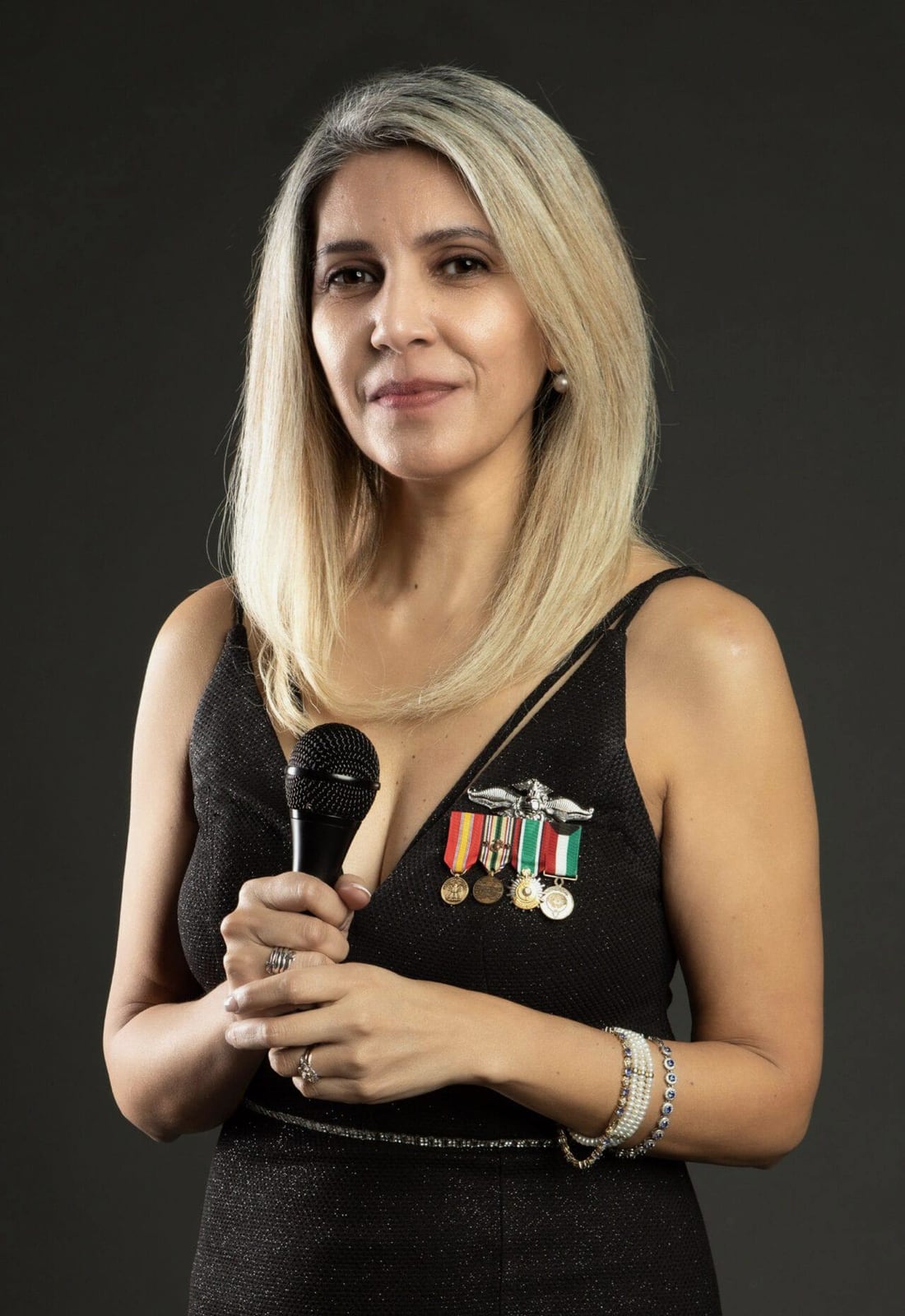 Cristie Remmel holding a microphone and wearing her service medals
